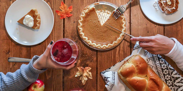 Birds eye view of a reclaimed wood dining table with pumpkin pies, bread and drinks