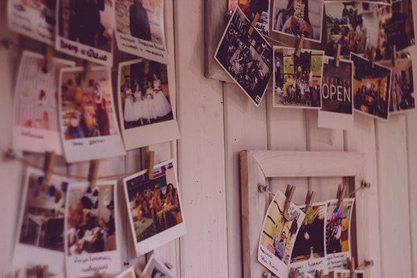 A wooden wall with strings of polaroid pictures