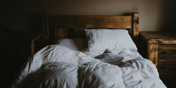 A rustic wooden bed with matching bedside tables and white bedding