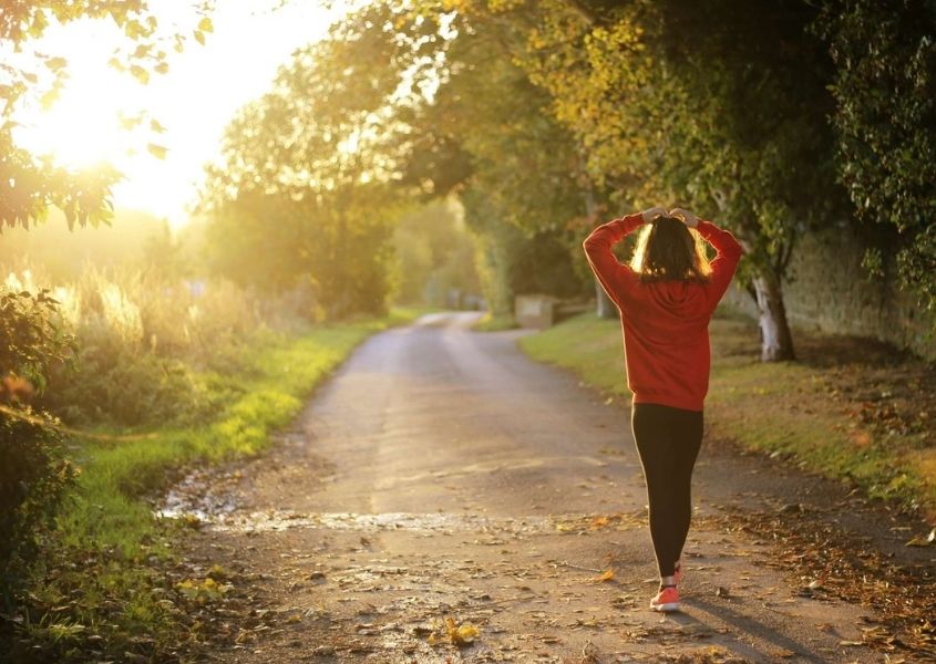 Women in red top walking along a track in the countryside in the sunlight