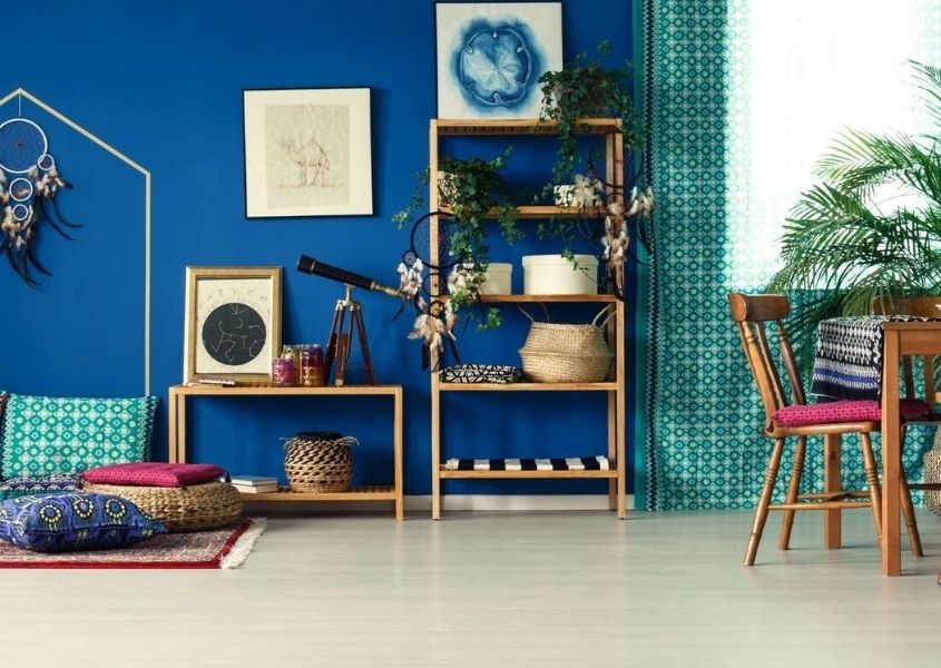 Blue living room with sheer green curtains and rugs and cushions on floor